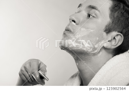 Young man shaving using razor with cream foam. Young man shaving using razor with cream foam. 123902564
