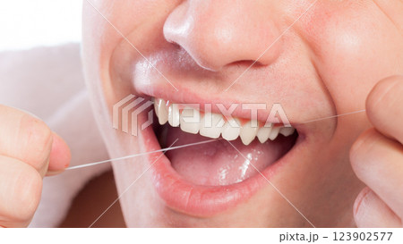 Young man cleaning her white teeth with dental floss Young man cleaning her white teeth with dental floss 123902577