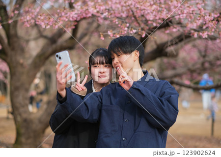 梅の花を背景に自撮り写真を撮るカップル 梅の花を背景に自撮り写真を撮るカップル 123902624