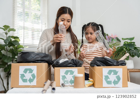 Sustainability and Family Learning. A mother guides her daughter on proper recycling techniques in their home. Sustainability and Family Learning. A mother guides her daughter on proper recycling techniques in their home. 123902852