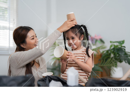 Sustainability and Family Bonding. A mother and daughter engaging in a fun recycling activity with paper cups and containers. 123902919
