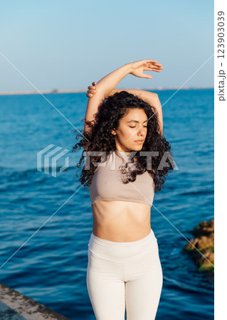 woman doing gymnastics yoga asana on the beach by the sea 123903039