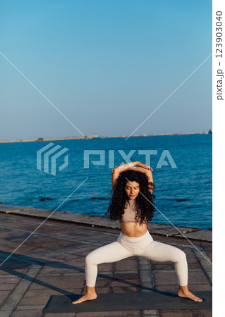 woman doing gymnastics yoga asana on the beach by the sea 123903040