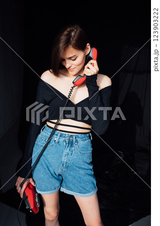 brunette woman smiling and talking on old corded phone 123903222
