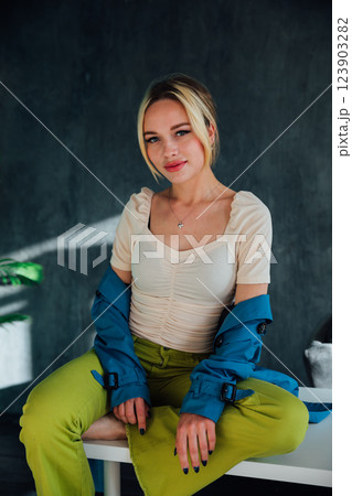 Beautiful slim fashion blonde woman sitting on a white table 123903282