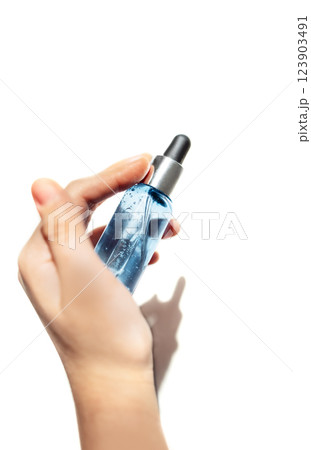 Close-up of a female hand with a transparent bottle of blue moisturizing serum for the face Close-up of a female hand with a transparent bottle of blue moisturizing serum for the face 123903491