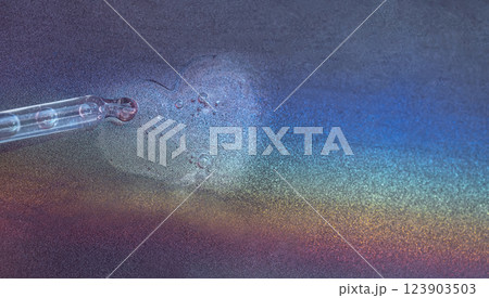 The banner is made with a glass pipette with transparent moisturizing facial serum on a rainbow background. Multicolored backdrop with sparkles with skin essence. The banner is made with a glass pipette with transparent moisturizing facial serum on a rainbow background. Multicolored backdrop with sparkles with skin essence. 123903503