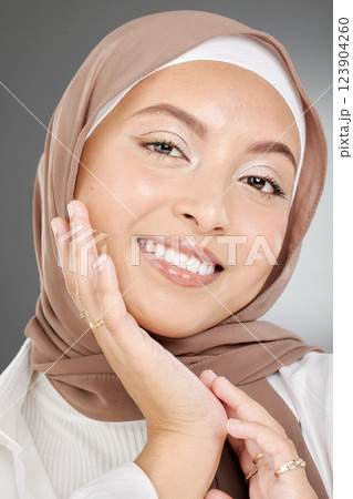 Muslim, beauty woman or arab model with smile for portrait, makeup or facial skincare in grey studio background. Skin, face or happy islamic girl with fashion, confident or headshot with brown hijab Muslim, beauty woman or arab model with smile for portrait, makeup or facial skincare in grey studio background. Skin, face or happy islamic girl with fashion, confident or headshot with brown hijab 123904260