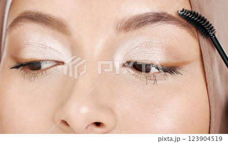 Beauty, muslim and makeup with eyebrow cosmetic tool for conservative glamour, style or elegance. Elegant eyeshadow look of islamic girl with hijab styling face with cosmetics brush close up. 123904519