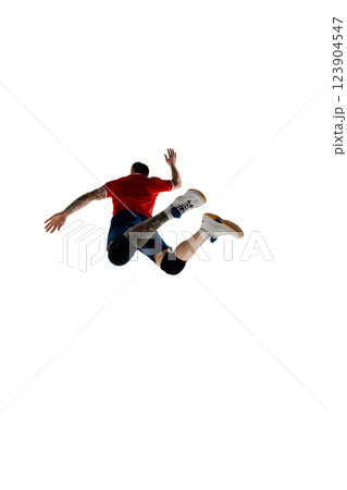 Low angle back view image of male volleyball player in mid-air, jumping high to hit the ball, training isolated on white background. 123904547