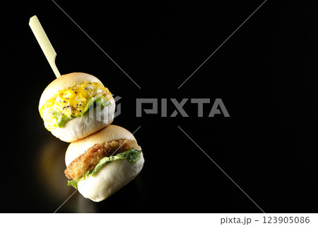 玉子とコロッケのミニハンバーガーを黒背景で撮影 123905086