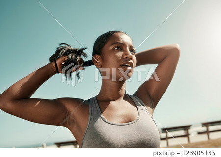 Woman tying her hair before an outdoor workout for fitness, health and wellness in nature. Training, sports and healthy girl athlete from Mexico preparing for a run or cardio exercise in a field. 123905135