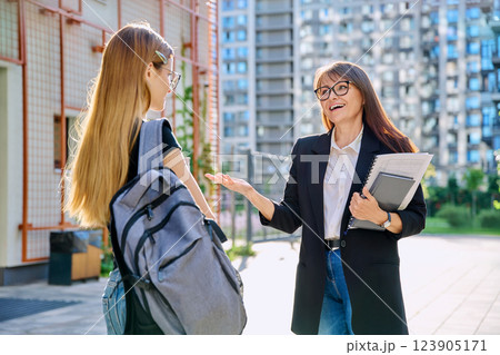Female teacher talking to teenage student girl, outdoor, educational building background 123905171