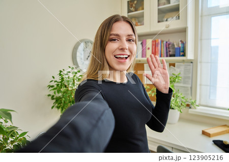 Close-up selfie portrait of young cheerful woman looking at web camera 123905216