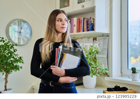 Portrait of woman university student holding textbooks notebooks, in home Portrait of woman university student holding textbooks notebooks, in home 123905229