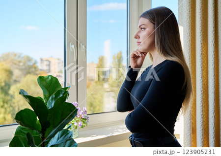 Relaxed calm young woman looking out the window at home Relaxed calm young woman looking out the window at home 123905231