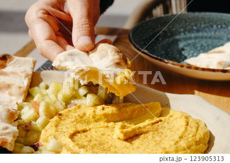 man dipping some naan bread on hummus man dipping some naan bread on hummus 123905313