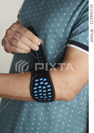 man adjusts his epicondylitis bracelet 123905319