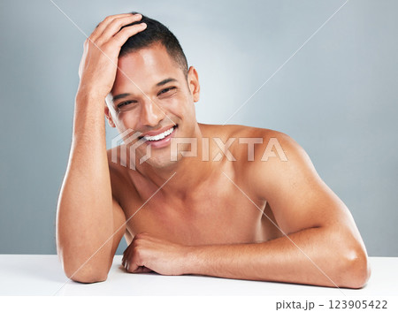 Man, smile and skin for beauty, skincare and health with shine, glow and body against grey background in studio. Model, cosmetics and healthy in dermatology portrait with face, cosmetic and wellness Man, smile and skin for beauty, skincare and health with shine, glow and body against grey background in studio. Model, cosmetics and healthy in dermatology portrait with face, cosmetic and wellness 123905422