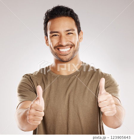Man, happy and portrait with thumbs up in studio for support, agreement and positive review of promotion. Success, person and like emoji on gray background for sale approval, yes sign and thank you 123905643