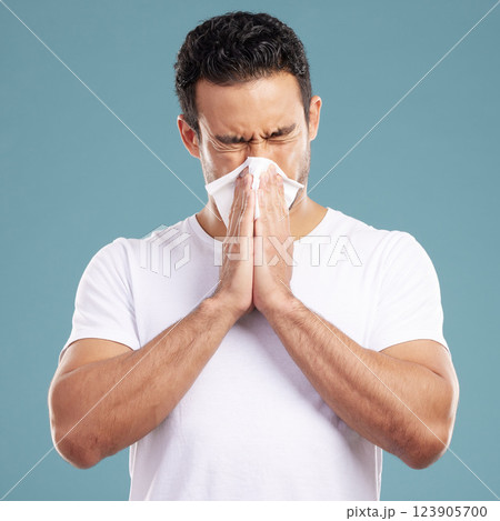 Tissue, sneeze and man in studio for sick, allergy and cold or influenza on blue background. Male model, hayfever and sinusitis or infection of virus with bacteria, health care and nasal congestion 123905700