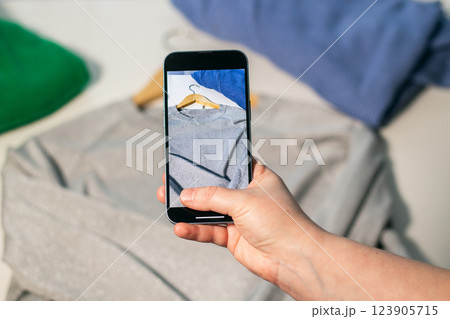 Woman taking photo of used clothes in good quality. Preparing to sell in second hand online market. Second hand and resale concept. Clothes donation. 123905715