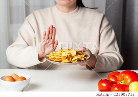 Closeup of woman making stop sign to refuse fried chips for dieting and healthy eating. Vegetable plate. Weight loss concept. Closeup of woman making stop sign to refuse fried chips for dieting and healthy eating. Vegetable plate. Weight loss concept. 123905718
