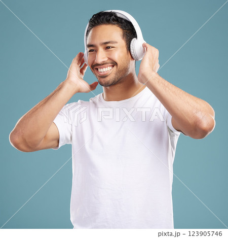 Studio, man and happy with headphones for music, podcast and satisfied with playlist for motivation. Smile, male person and model for listening to audio, streaming sound and radio by blue background 123905746