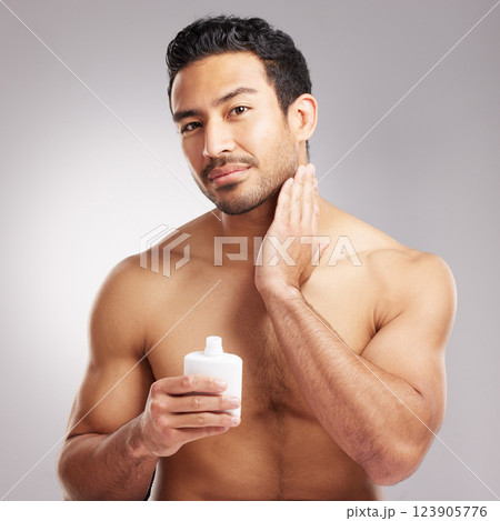 Beauty, cream and portrait of man in studio to apply lotion for cosmetics or dermatology routine. Aesthetic, moisturizer and skincare with shirtless model on gray background for antiaging cosmetology Beauty, cream and portrait of man in studio to apply lotion for cosmetics or dermatology routine. Aesthetic, moisturizer and skincare with shirtless model on gray background for antiaging cosmetology 123905776