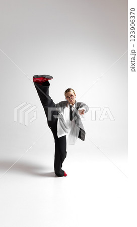 Expressive movement of young female professional, dressed oversized jacket, flowing in motion against white background. 123906370