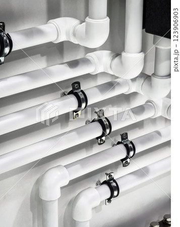 Detailed view of white plumbing pipes installed on a wall in a modern building environment 123906903