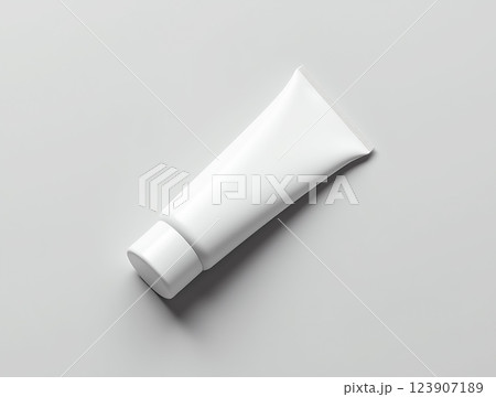 White tube container lying flat on a smooth surface highlighting modern design and minimalist aesthetics White tube container lying flat on a smooth surface highlighting modern design and minimalist aesthetics 123907189