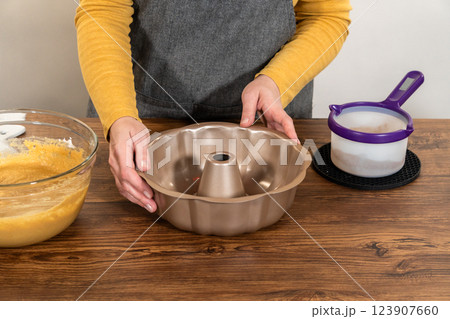 Carefully greasing a bundt cake pan in preparation for baking a delicious gingerbread bundt cake with caramel frosting. 123907660