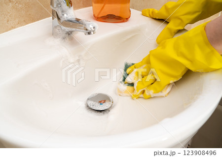 Cleaning bathroom basin and water tap, yellow gloves and spray detergent 123908496
