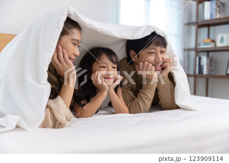 Happy father mother daughter lie down and play on bed. Mom dad and little girl smiling cheerful bedroom. relaxing in holiday. Happy father mother daughter lie down and play on bed. Mom dad and little girl smiling cheerful bedroom. relaxing in holiday. 123909114