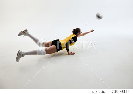 Dynamic image of determined athlete, young woman playing volleyball, hitting ball isolated on white studio background. Dynamic image of determined athlete, young woman playing volleyball, hitting ball isolated on white studio background. 123909315