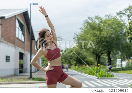 Young beautiful woman sportswear workout clothes using smartphone and listening to music with headphones standing relax in park during exercise the morning. fitness healthy concept. 123909913