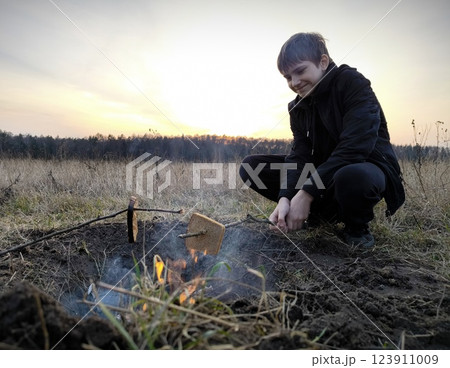 Happy children sitting around campfire, Happy teenager in nature by the campfire. Concept of camping Happy children sitting around campfire, Happy teenager in nature by the campfire. Concept of camping 123911009