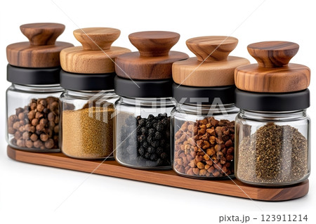 Spice jars with wooden lids containing different spices resting on wooden base 123911214