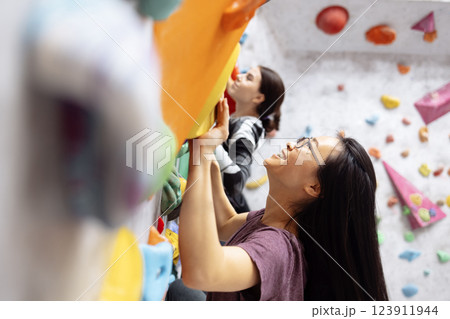 A group of multiracial women doing rock climbing in the gym. A group of multiracial women doing rock climbing in the gym. 123911944
