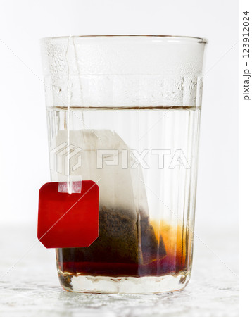 Faceted glass of boiled water and tea bag Faceted glass of boiled water and tea bag 123912024