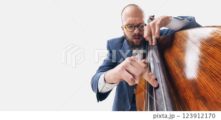 Close-up of man in glasses, jazz musician focusing on bass strings, deeply immersed in rhythm and sound on whit background 123912170