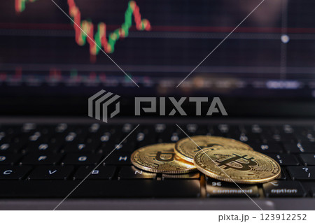 golden bitcoins on laptop keyboard with cryptocurrency trading chart on screen, digital currency investment concept golden bitcoins on laptop keyboard with cryptocurrency trading chart on screen, digital currency investment concept 123912252
