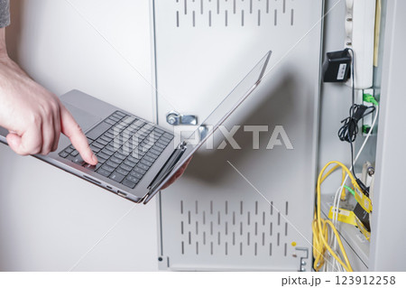 technician using laptop to configure network server in data cabinet for IT maintenance and troubleshooting technician using laptop to configure network server in data cabinet for IT maintenance and troubleshooting 123912258