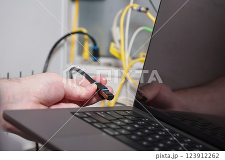 technician connecting ethernet cable to laptop for high speed internet, IT network setup and data transfer in server room technician connecting ethernet cable to laptop for high speed internet, IT network setup and data transfer in server room 123912262