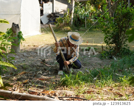 Asian adult woman working outdoors in summer garden. 123913625