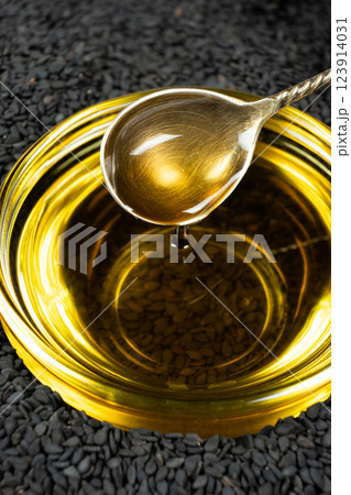 Black sesame oil poured from a spoon into a glass bowl 123914031