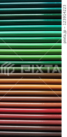 Close-up of neatly stacked colored pencils arranged in a gradient from green to brown and red tones.  The glossy texture reflects light, creating a visually appealing pattern. 123914223