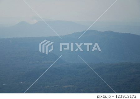 View of misty mountains with layered blue hues during a quiet afternoon 123915172
