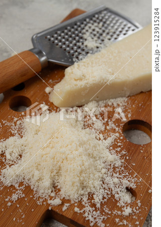 Freshly sliced and grated cheese, parmesan cheese, on a wooden chopping board, rustic style, no people 123915284